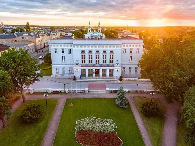 Na zdjęciu budynek Urzędu Miasta widok z góry, widac bryłę budynku oraz trawnik przed Urzędem z utworzonym z roślin konturem Polski 