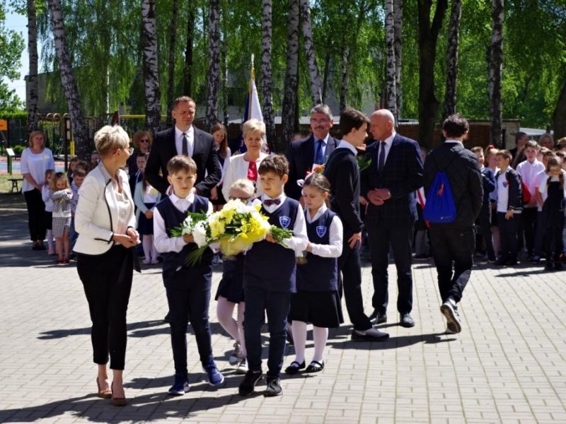 Na zdjęciu dzieci składające kwiaty podczas Dnia Patrona w SP nr 12.